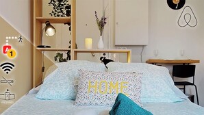 Quarto bem arrumado com cama, mesa de cabeceira, escrivaninha e cadeira.