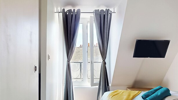 Quarto com cama, cortinas, TV de tela plana e janela.