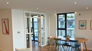 Un interior moderno con comedor, un ventanal grande y obras de arte en las paredes.