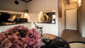 Eine moderne Küche mit Essbereich, ausgestattet mit einer großen Blumenanordnung, einer Champagnerflasche und einem Esstisch mit Stühlen.