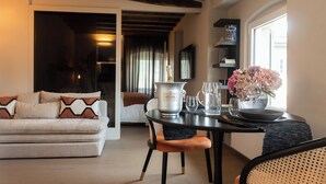 Ein modernes Wohnzimmer mit einer Couch, einem Esstisch, einer Flasche Taittinger Champagner, Gläsern und einem Blumenstrauß.