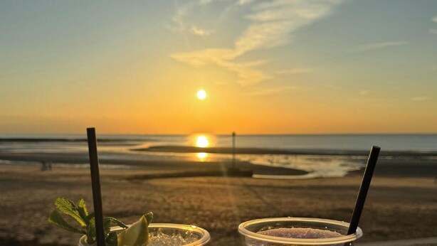 Blick auf einen Strand, im Vordergrund Getränke.