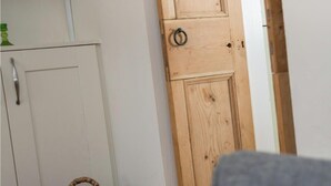 Ein Zimmer mit einer Holztür, einem weißen Schrank und einer grünen Vase.