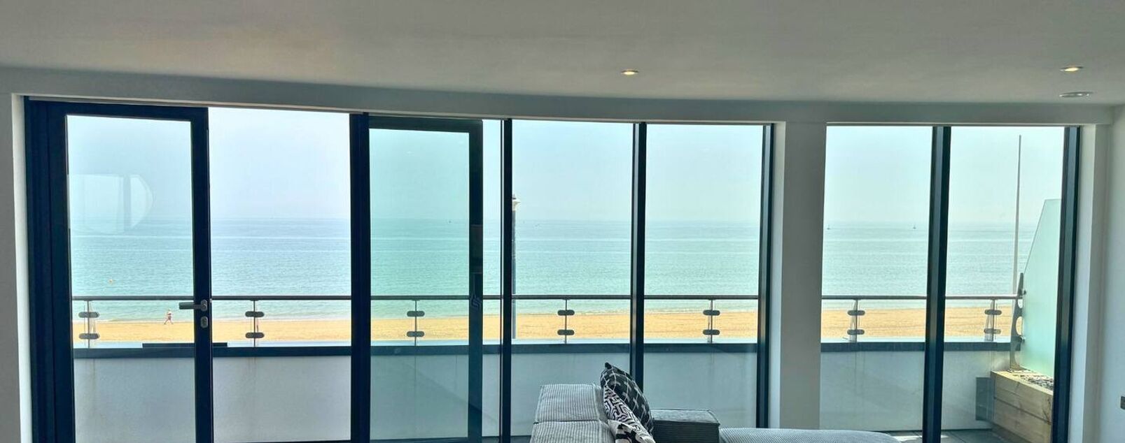 A room with large windows overlooking a beach and the ocean.