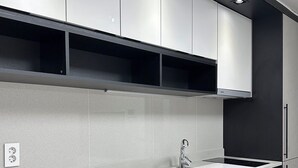 A modern kitchen with white cabinets, a stainless steel sink, and a black countertop.