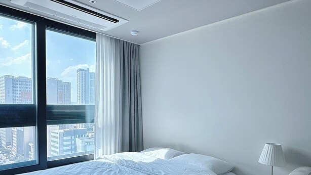 Ein modernes Hotelzimmer mit großem Fenster, einem Bett, einem Nachttisch und einer Lampe.