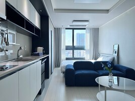 Una habitación de hotel moderna con kitchenette, una cama grande, zona de estar y vistas a la ciudad.