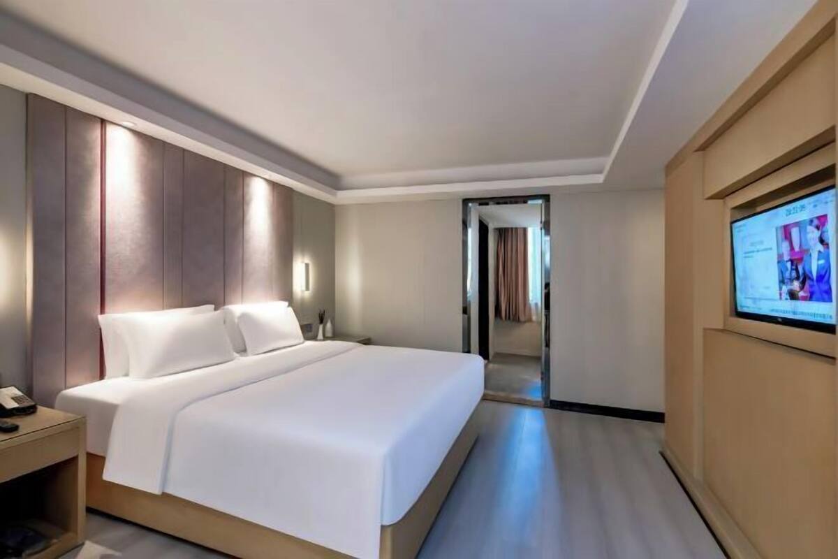 A hotel room with a bed, bedside table, and a TV screen.
