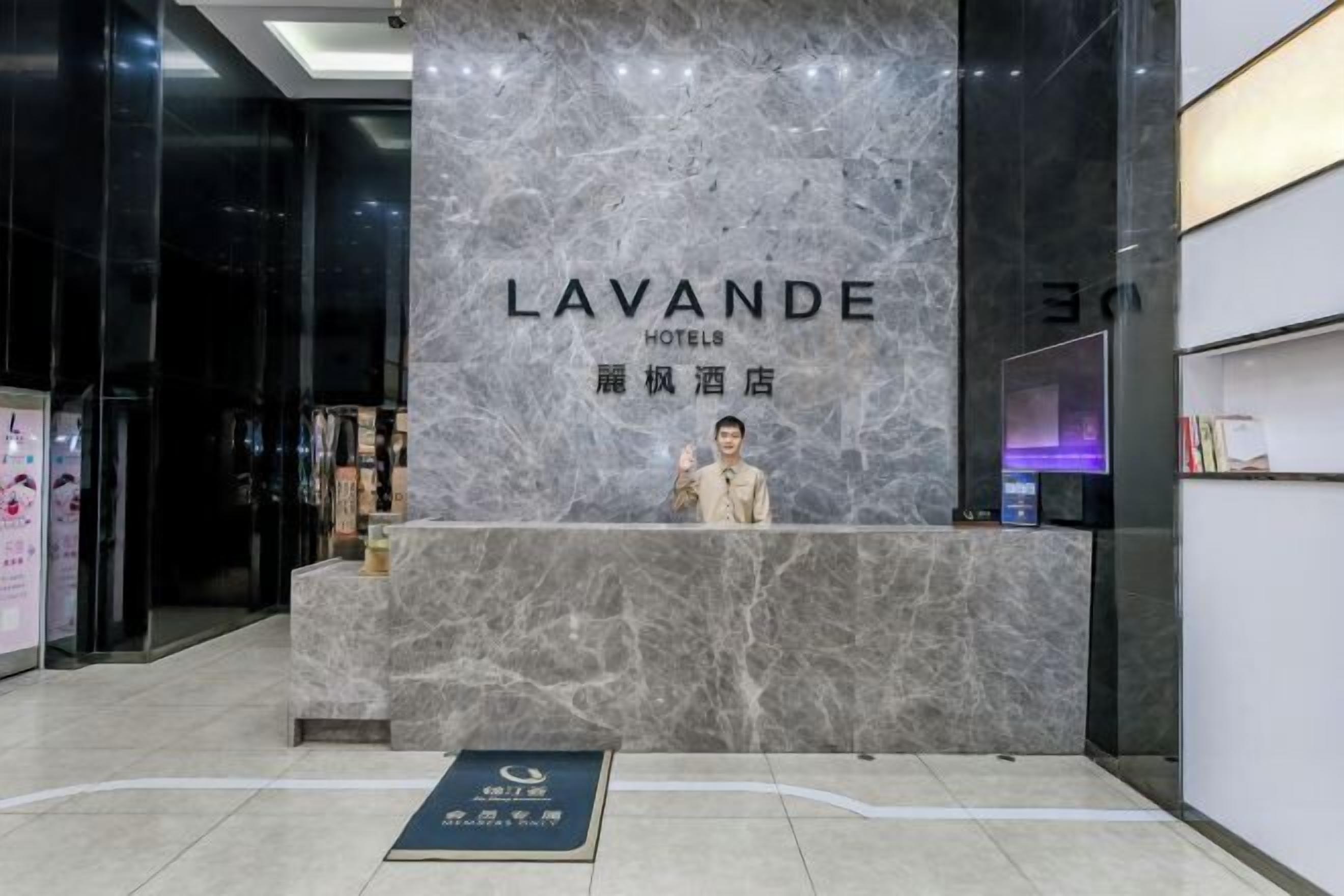 A reception desk with a marble wall and a sign reading "LAVANDE HOTELS".