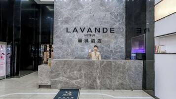 A reception desk with a marble wall and a sign reading "LAVANDE HOTELS".
