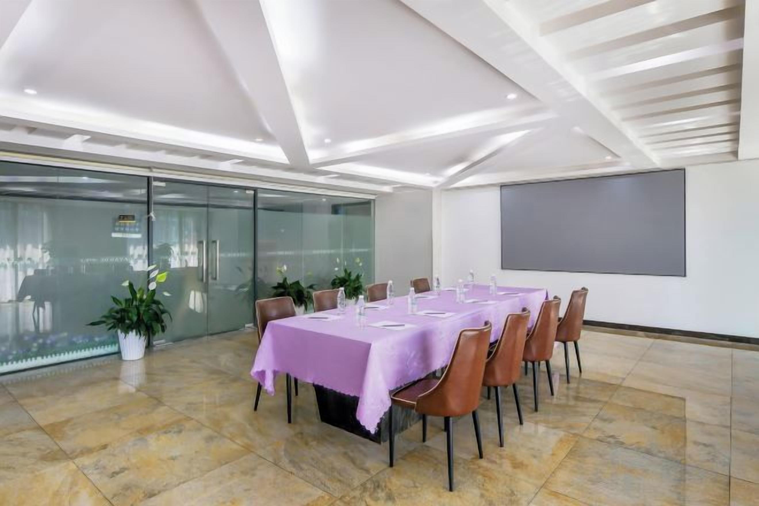 Una sala de conferències amb una taula llarga, cadires i una pantalla projectora.