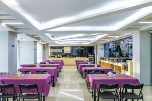 A dining area with tables and chairs, a kitchen in the background, and a ceiling with recessed lighting. - Lavande Hotel (Chongqing Guanyinqiao Pedestrian Street) (Chongqing)