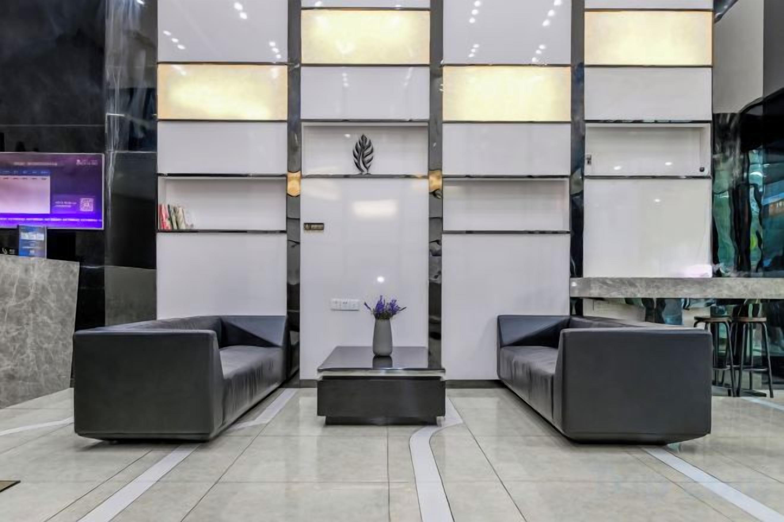 Un vestíbul modern amb dos sofàs, una taula central i una planta decorativa.