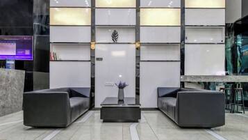 Un vestíbul modern amb dos sofàs, una taula central i una planta decorativa.