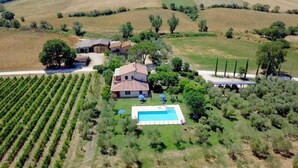 Una propietat amb piscina, una casa espaiosa i files de vinyes.