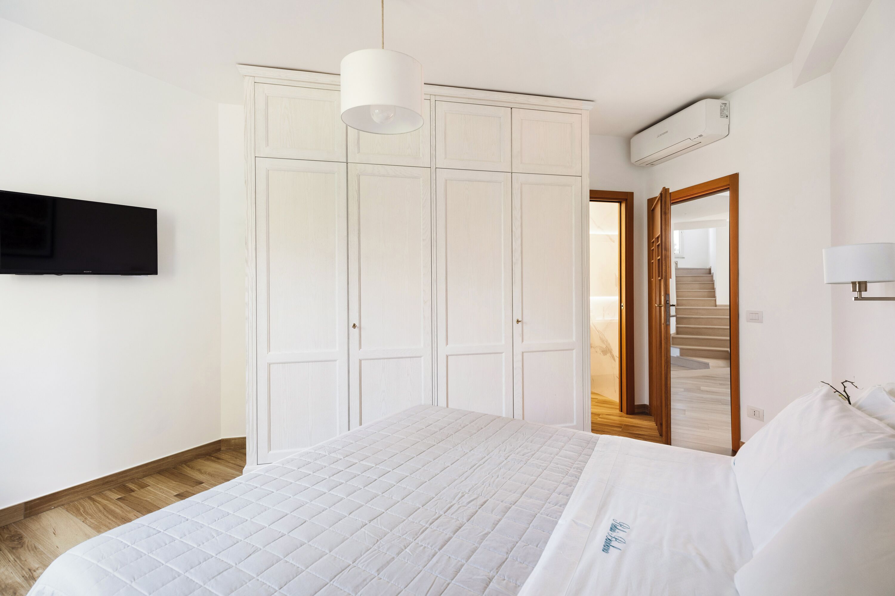 Ein Schlafzimmer mit Bett, Kleiderschrank, Fernseher und Klimaanlage.