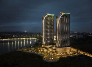 Two high-rise buildings with a curved design, surrounded by a landscaped area with a road and a body of water. - Birkin International Hotel (Malacca City)