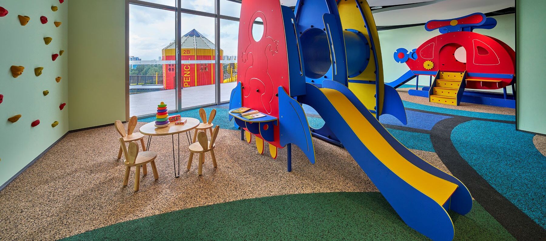 A children's play area with a slide, climbing wall, and a table with chairs.