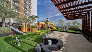 Relax in the resort's outdoor recreational area, featuring a grassy lawn and a play structure for kids.