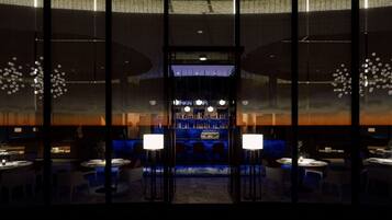 A modern bar area with a central bar, seating, and ambient lighting.