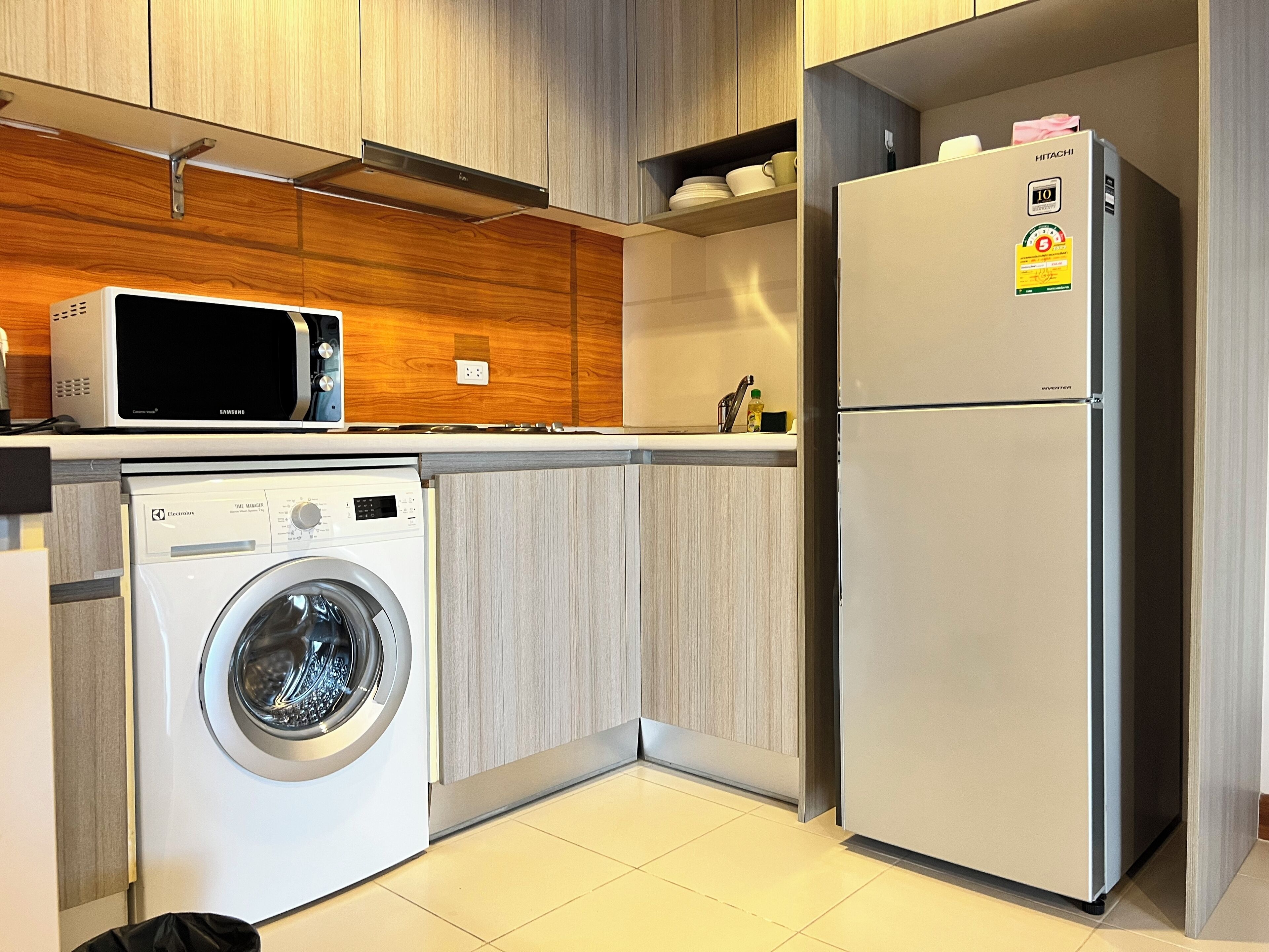 A compact kitchen with a washing machine, microwave, and refrigerator.