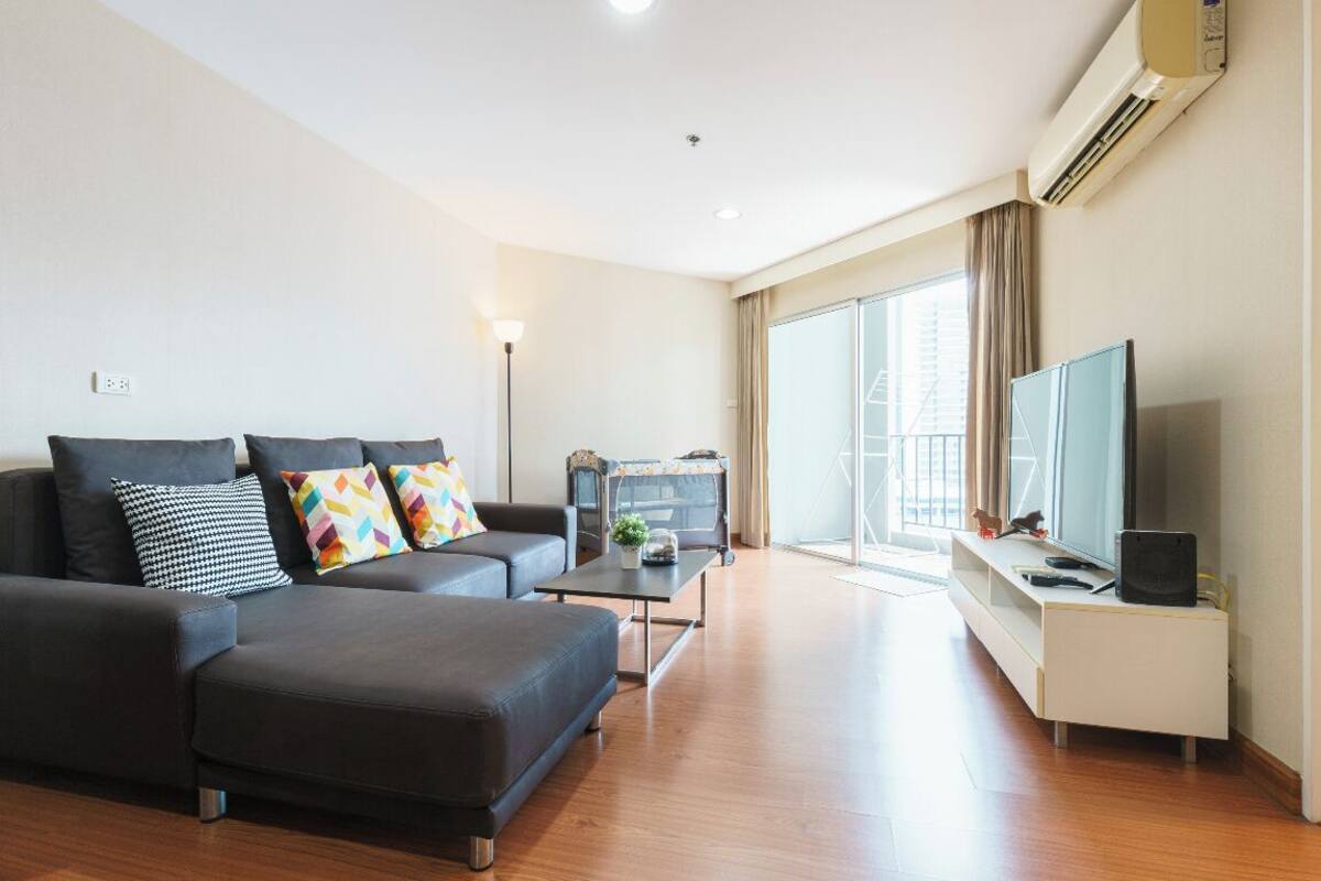 A modern living room with a sofa, a coffee table, a TV, and a sliding door to a balcony.