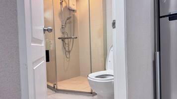A modern bathroom with a glass-enclosed shower, a toilet, and a white sink.