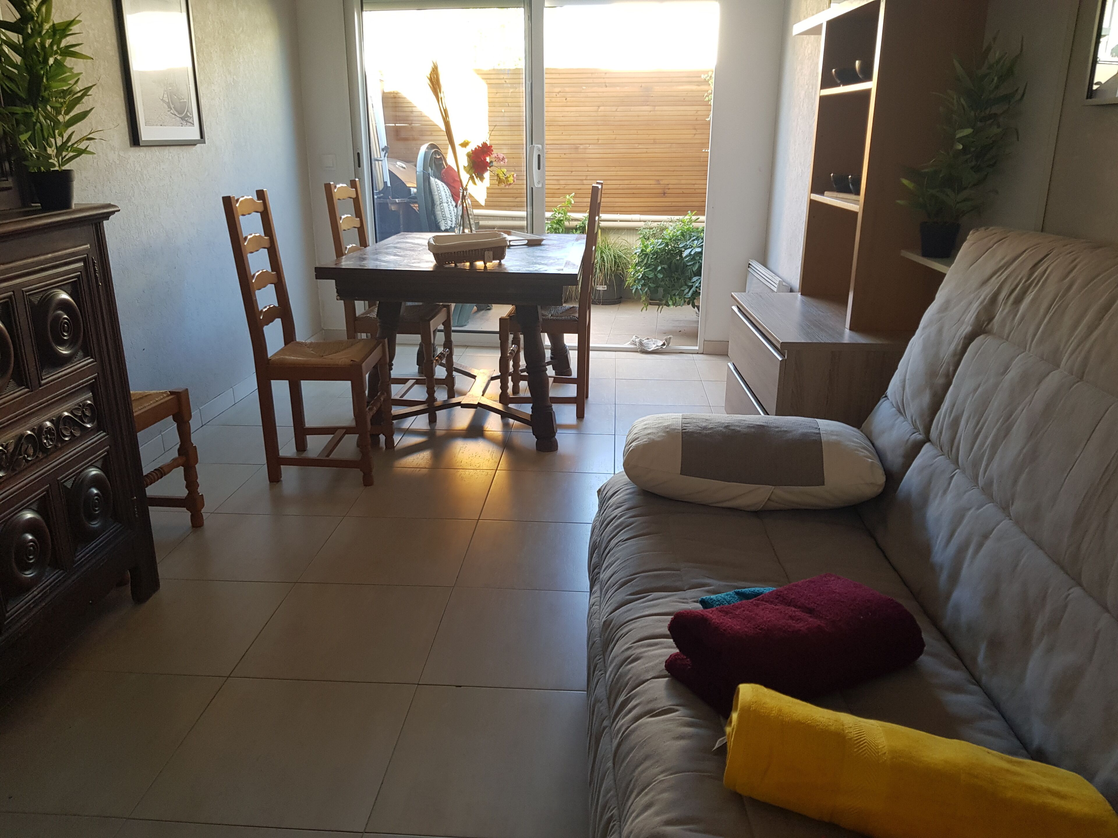 A living room with a sofa, a dining table, chairs, and a wooden cabinet.