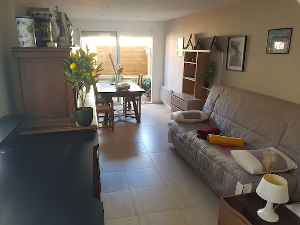 Sala de estar com sofá, mesa de jantar e área de cozinha.