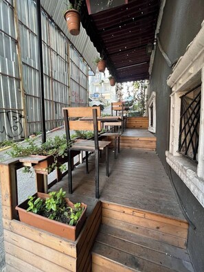 A covered outdoor seating area with wooden benches and planters. - Lovely coy flat in Taksim (Istanbul)