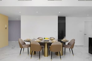 A modern dining area with a round table set for six, surrounded by six chairs, and a black cabinet to the right.