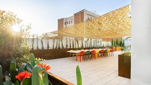 An outdoor patio with a long table and chairs, surrounded by plants and a decorative canopy. - Students Studios - Student Accommodation Only (Barceelona)