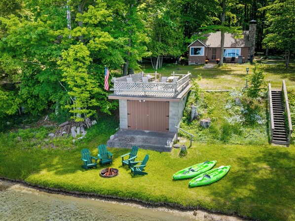 Un chalet au bord du lac, doté d’une terrasse, de meubles d’extérieur, de kayaks et d’un drapeau.