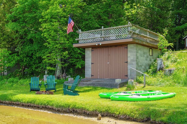 A cabin with a small deck, two Adirondack chairs, a kayak, and an American flag. - CRO Terrapin Station- 2 Cottages on Glen Lake (Maple City)
