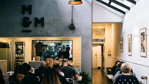 Ein Restaurant mit einem gut sichtbaren Schild mit der Aufschrift "MGM" und einem modernen Interieur, inklusive einer hängenden Leuchte.