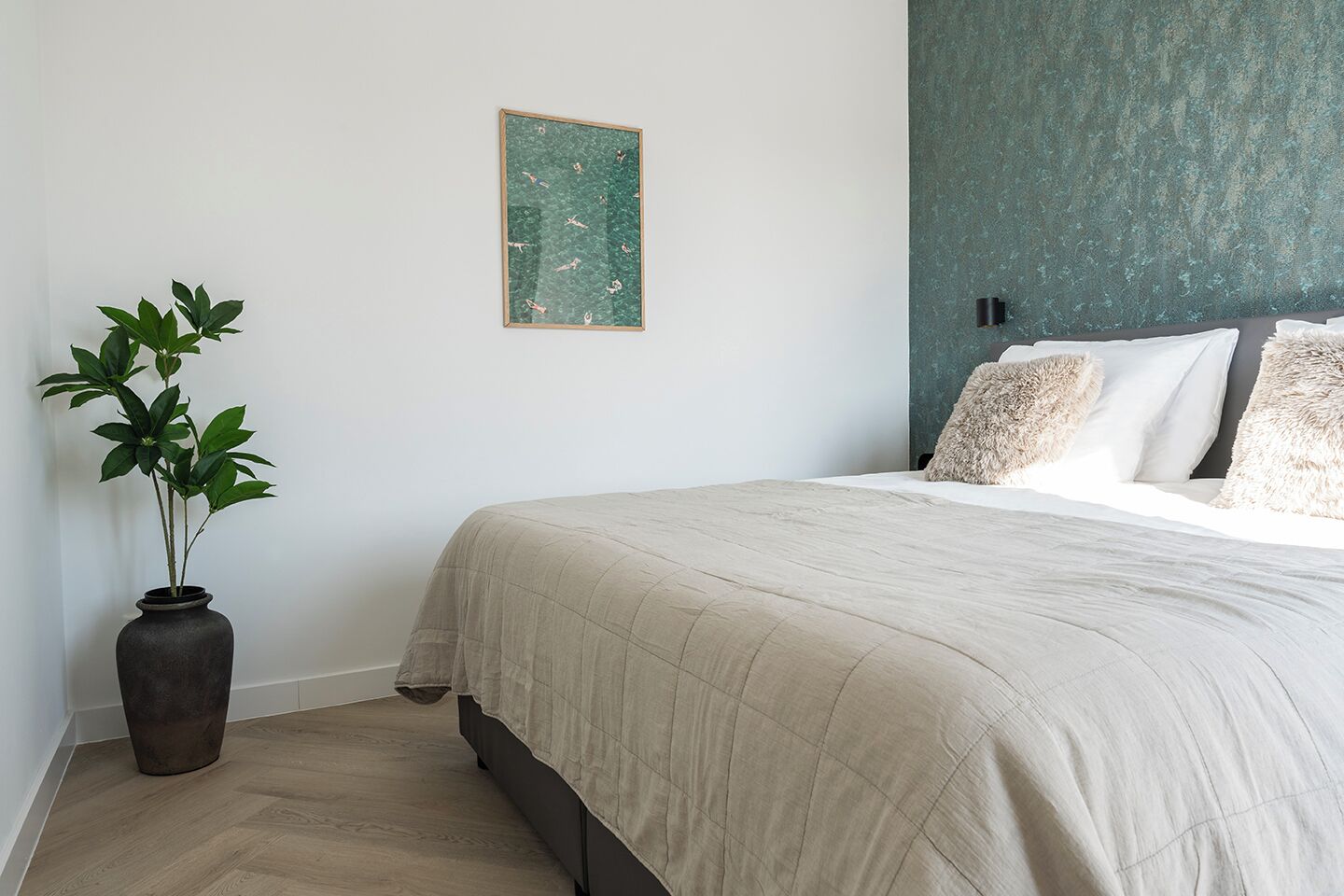 Ein Schlafzimmer mit einem Bett, einer Topfpflanze und einer strukturierten Wand.