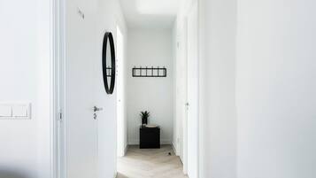 A hallway with white walls, a black circular decoration, a black rectangular object, and a small plant on a black base.
