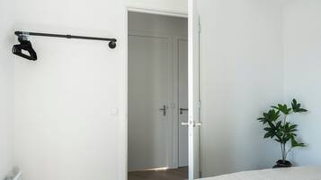 Une chambre à coucher avec un lit, une porte donnant sur une autre pièce, un radiateur et une plante en pot.