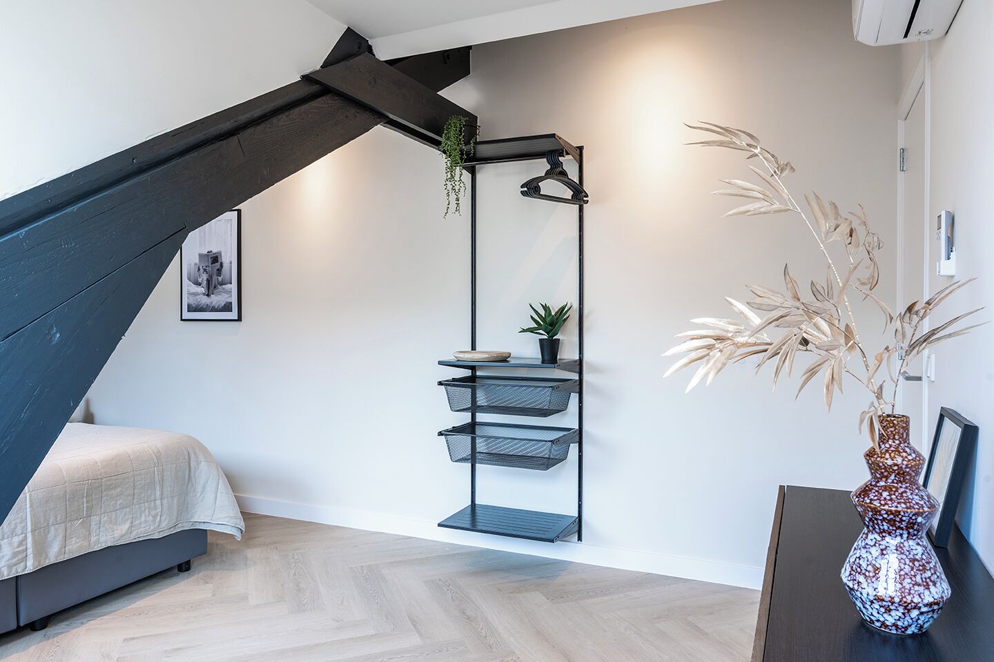 Une chambre moderne avec un plafond en pente, un lit, une étagère murale agrémentée de plantes et un vase décoratif.
