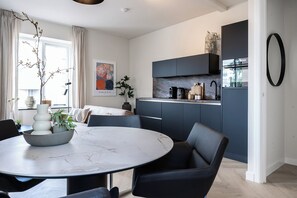 Een moderne keuken met donkere kastjes, een marmeren aanrecht en een inbouwoven.