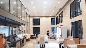 A spacious, well-lit indoor area with a long counter, multiple tables, and chairs arranged for dining or meetings.