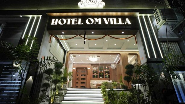 The entrance of Hotel Om Villa with a modern design, featuring a staircase, potted plants, and a sign with the hotel's name. - Hotel Om Villa (Varanasi)