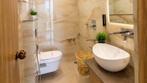 A modern bathroom with a glass-enclosed shower, a white toilet, a sink with a mirror, and a wooden vanity. - Hotel Om Villa (Varanasi)