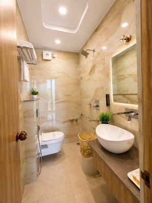 Une salle de bain moderne avec une douche à parois de verre, des toilettes blanches, un lavabo avec un miroir et un meuble-lavabo en bois.