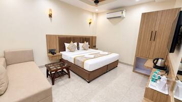 Habitación de hotel con cama, sofá, una mesita, aire acondicionado, televisión y kitchenette.