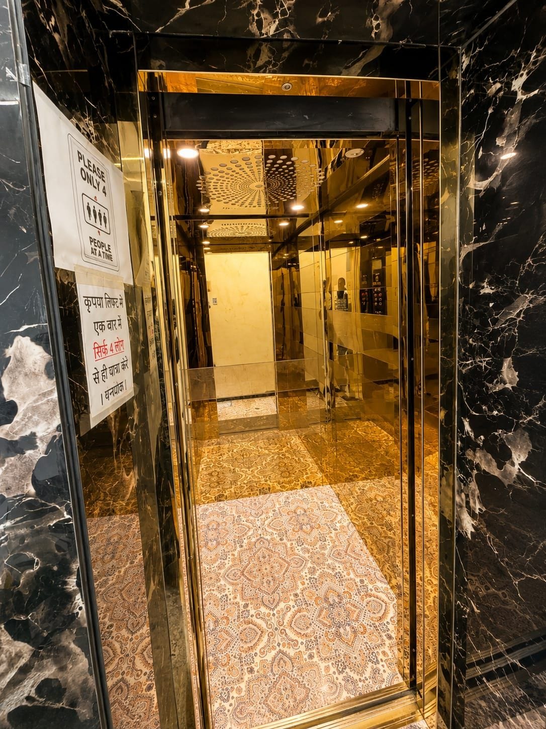Un ascenseur avec un intérieur en marbre et un tapis à motifs.