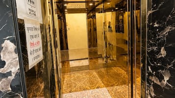 Elevador com interior em mármore e carpete estampado.