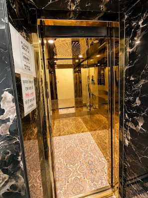 An elevator interior with a marble floor and glass walls.