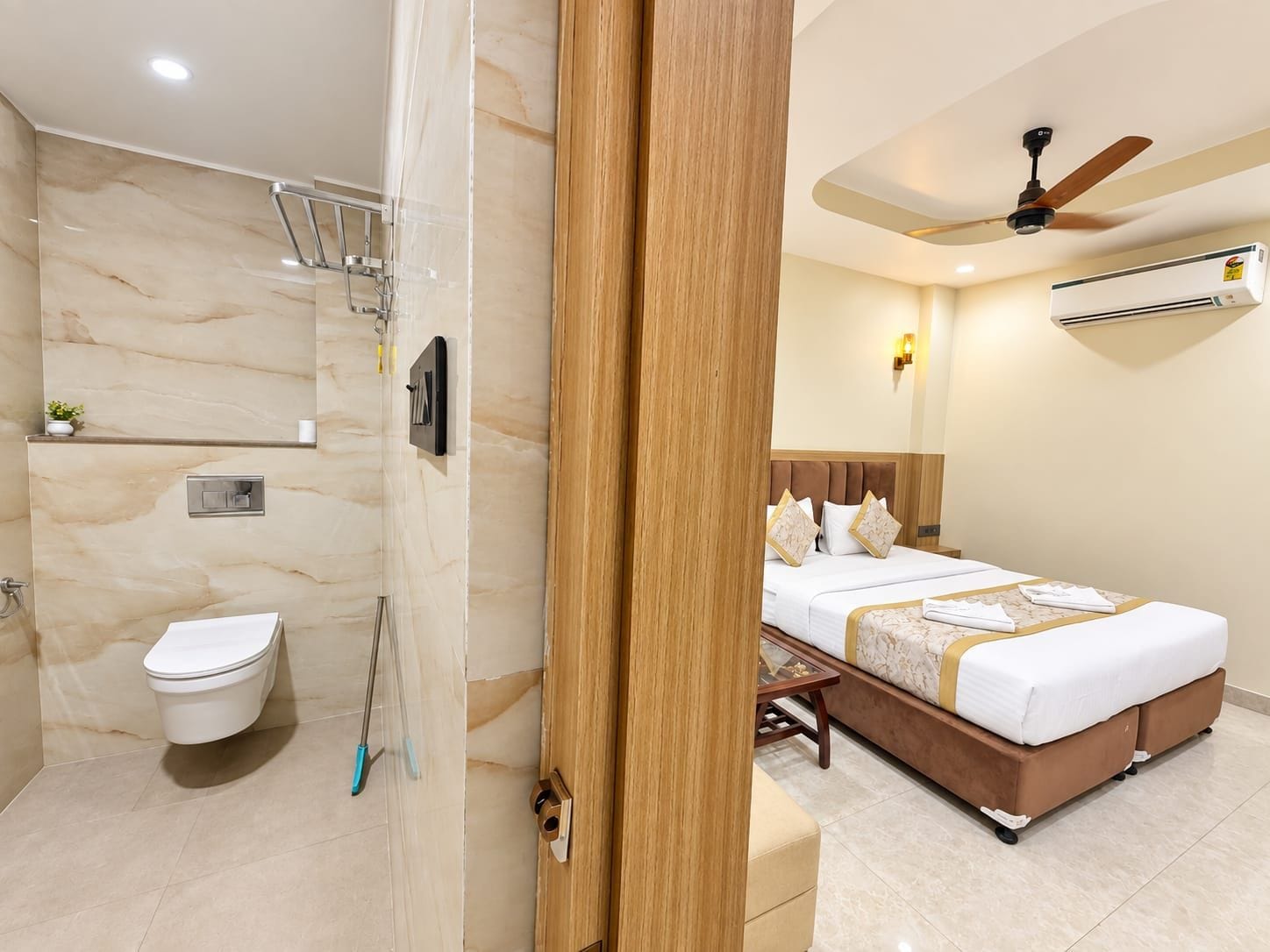 A hotel room with a shower, toilet, bed, and a ceiling fan.