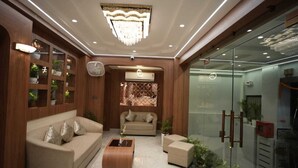 A modern living room with a beige sofa, a wooden coffee table, and a glass partition. - Hotel Om Villa (Varanasi)